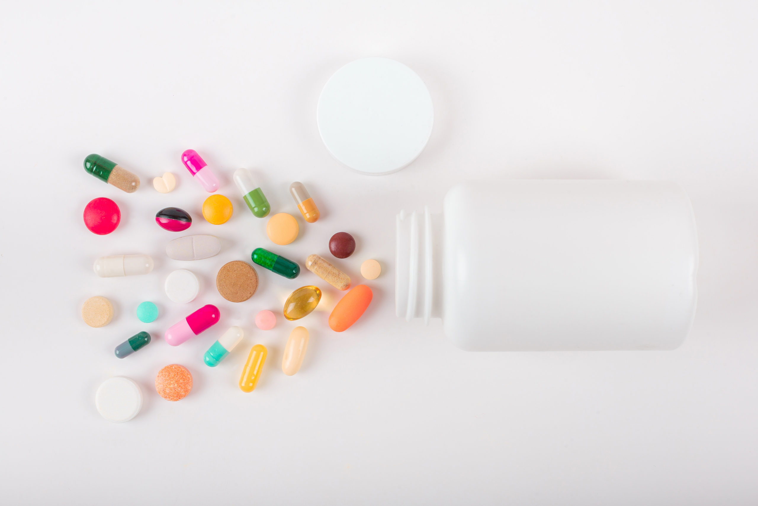 Assorted pharmaceutical medicine pills, tablets and capsules and bottle on white background. Copy space for text